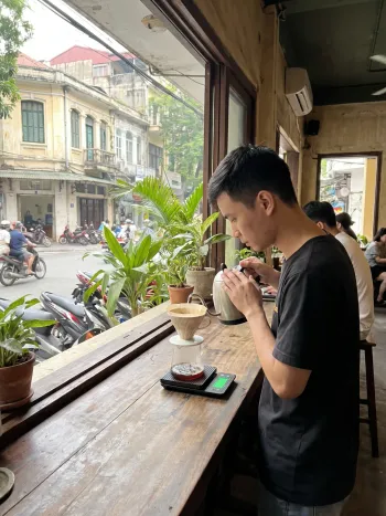 A barista meticulously preparing a V60 pour over on a digital scale